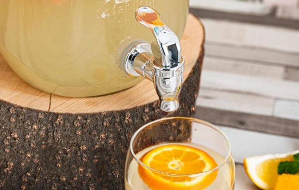 Un dispensador de bebidas de vidrio con agua y frutas frescas. Un dispensador de bebidas de vidrio con agua y frutas frescas.